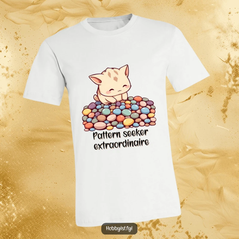 Funny curious creature with pointy ears meticulously arranging colorful pebbles into a pattern, on a comfortable t-shirt.